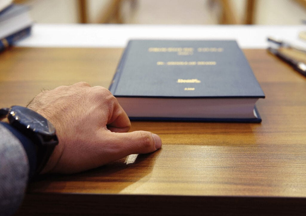 man with hand on desk about to open law book