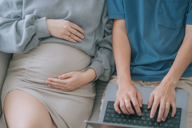 A pregnant woman and her husband lounging on their sofa